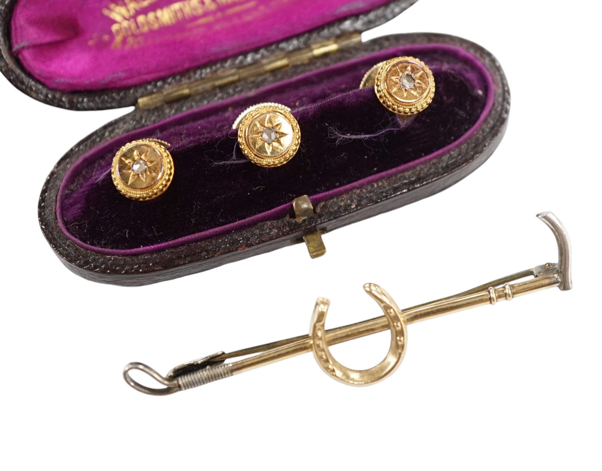 An Edwardian cased set of three 9ct and rose cut diamond set dress studs and a 9ct and silver riding crop and horseshoe bar brooch. Condition - fair